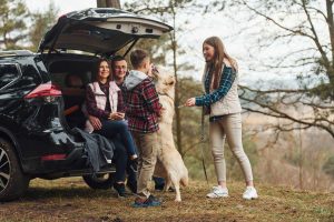 happy family hanging out at the back of their car with their dog